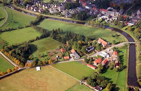 luchtfoto van stadje en landbouwgrond waar een riviertje doorheen slingert