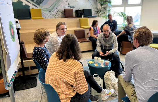 Vijf deelnemers van het minicongres Omgevingswet met elkaar in gesprek rond een tafel met een flip-over.