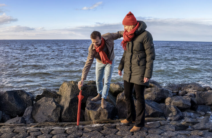 Man en vrouw op waterkering. Op de achtergrond water en lucht op de voorgrond de stenen kade