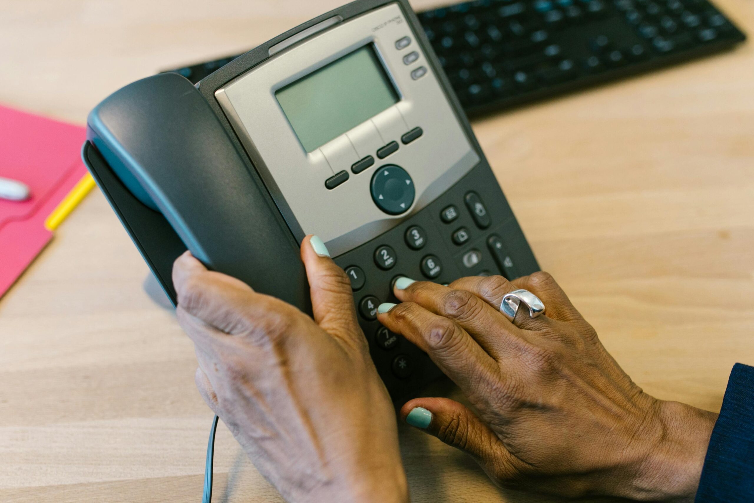 Tradionele telefoon. Een hand wil de hoorn oppakken en de andere hand wil nummers in toetsen